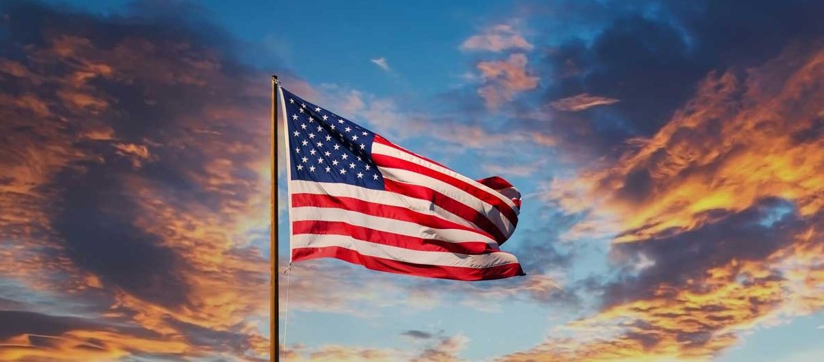 An American flag waving against a sunset sky.