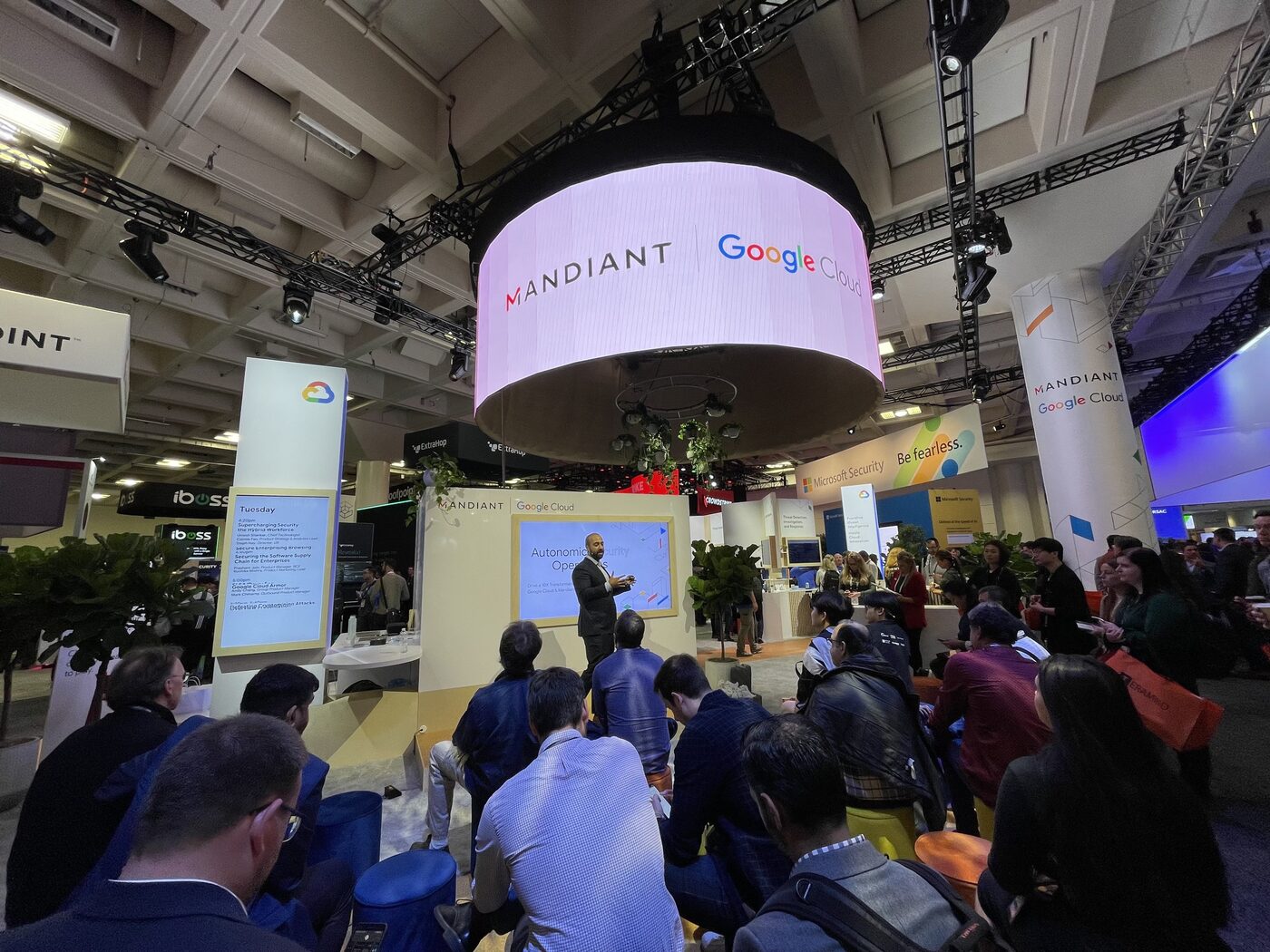 Iman Ghanizada presenting at the Google Cloud and Mandiant booth on a conference expo floor.
