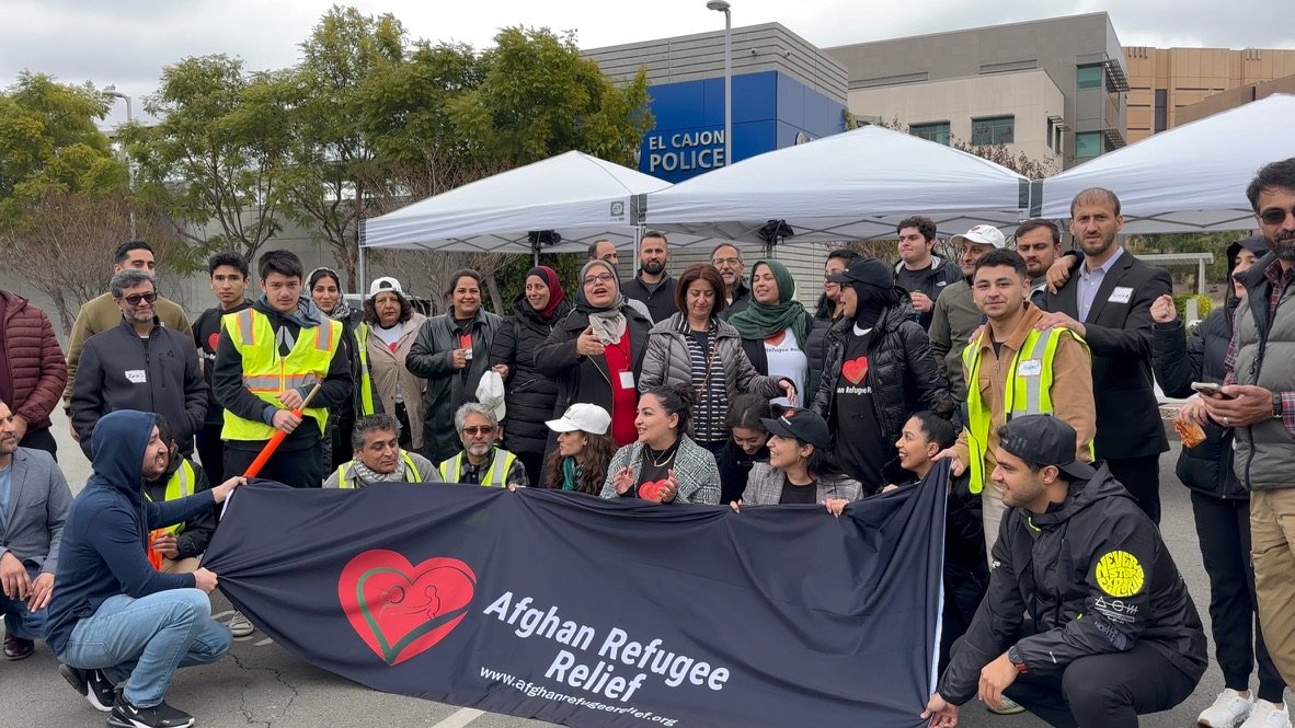 Afghan Refugee Relief volunteers gathered behind the organization's banner.